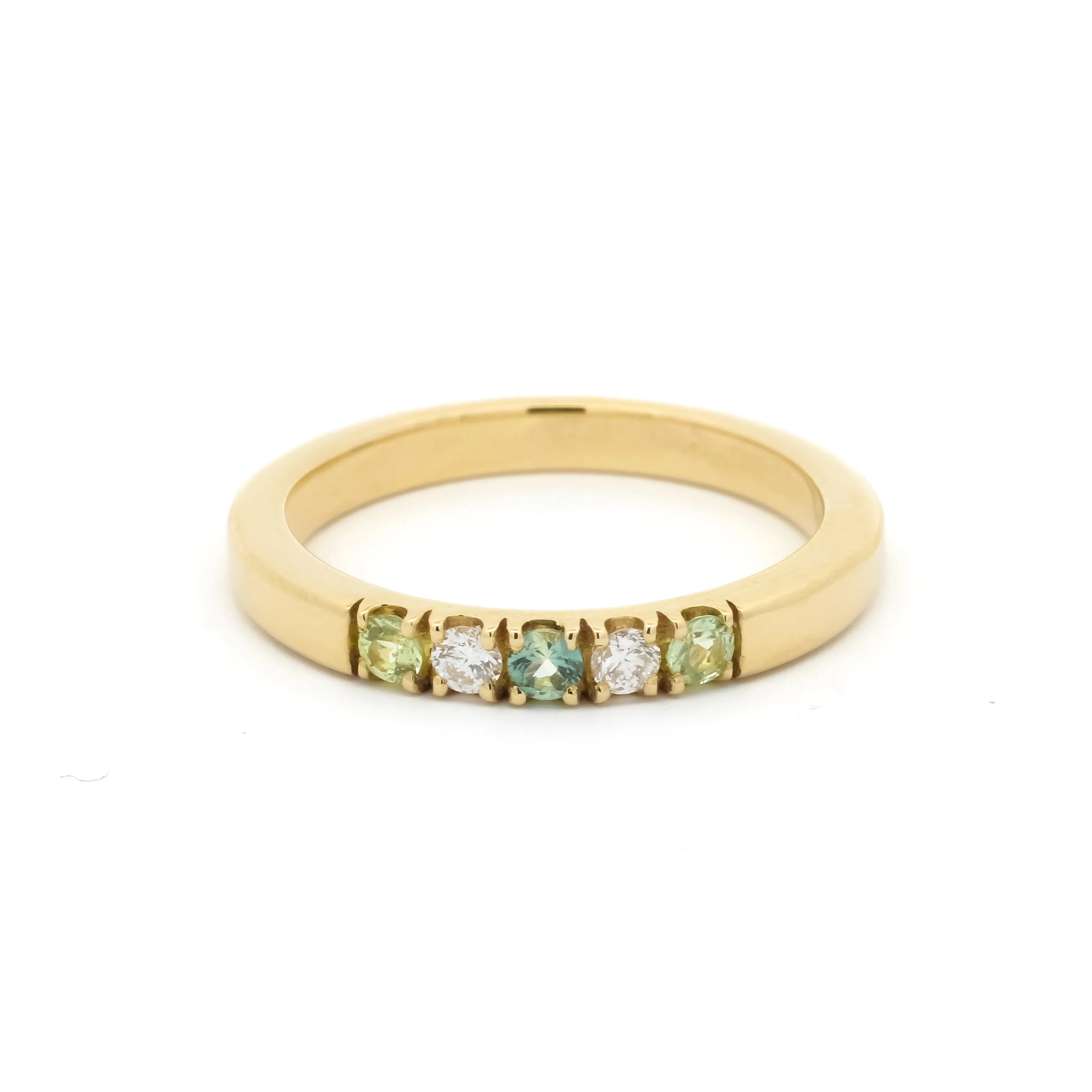 Gold ring with green gemstones on a white background