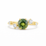 Gold ring with a green gemstone and smaller diamonds on a white background