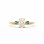 Gold ring with a central diamond flanked by two smaller diamonds on a white background