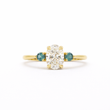 Gold ring with a central diamond flanked by two smaller diamonds on a white background