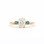Gold ring with a central diamond flanked by two smaller diamonds on a white background