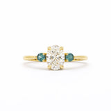 Gold ring with a central diamond flanked by two smaller diamonds on a white background
