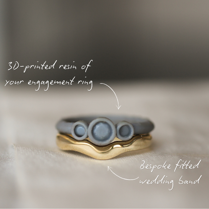 3D-printed resin engagement ring and bespoke fitted wedding band on a soft surface.