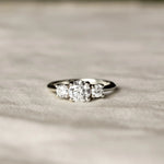 Trilogy Diamond White Gold Engagement Ring with three diamonds on a beige fabric surface