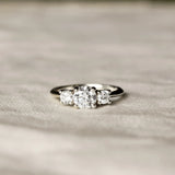 Trilogy Diamond White Gold Engagement Ring with three diamonds on a beige fabric surface