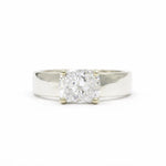 wide band white gold engagement ring with cushion cut diamond on a white background