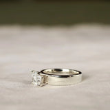 side view of chunky wide band engagement ring with cushion cut diamond and blurred background