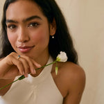 bride holding a white flower wearing blue sapphire engagement ring and diamond drop earrings