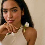 bride holding a white flower wearing blue sapphire engagement ring and diamond drop earrings