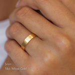 close up of hand wearing 5mm wide flat brushed wedding ring in 18ct yellow gold
