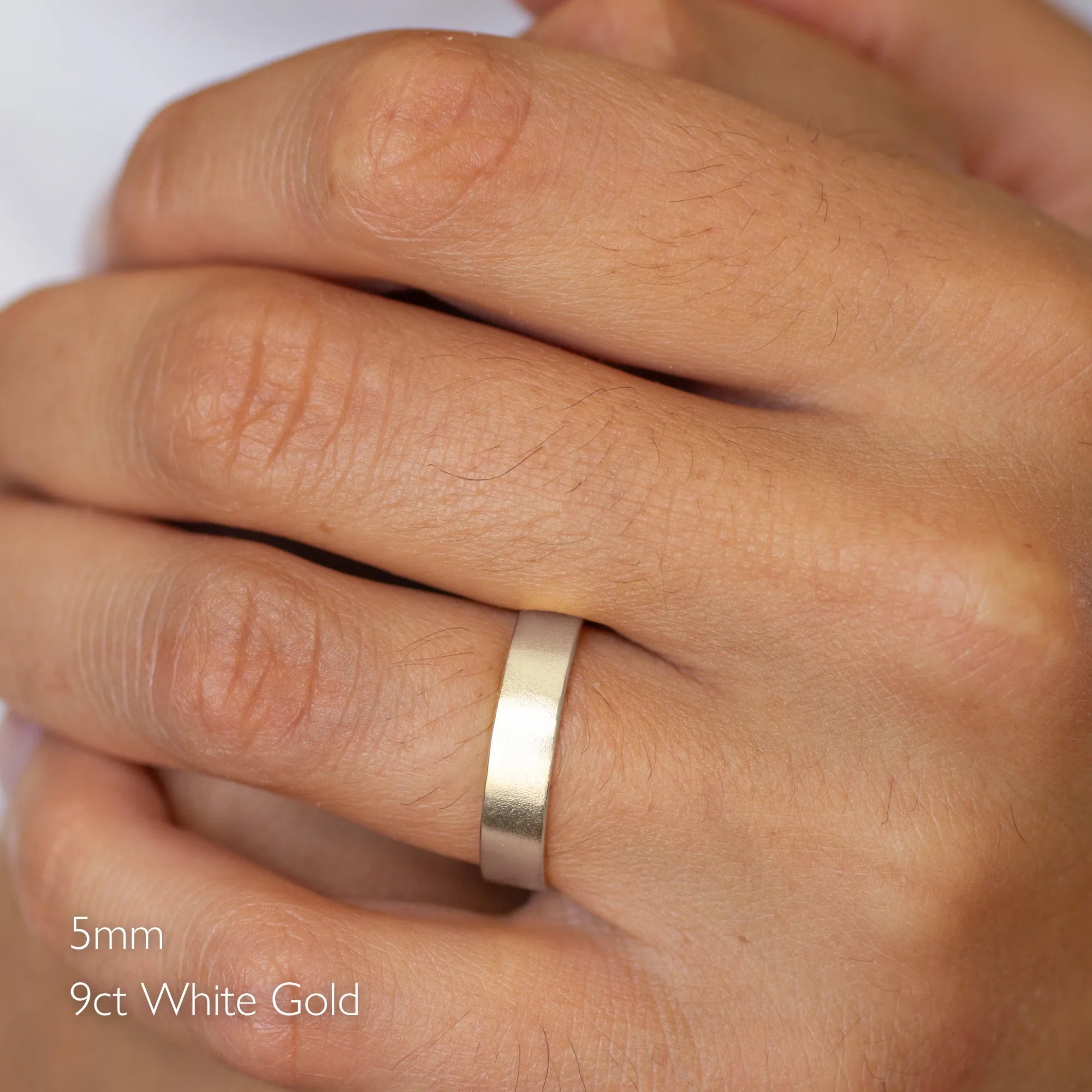 Gold satin flat wedding ring on a hand with '5mm 9ct White Gold' text