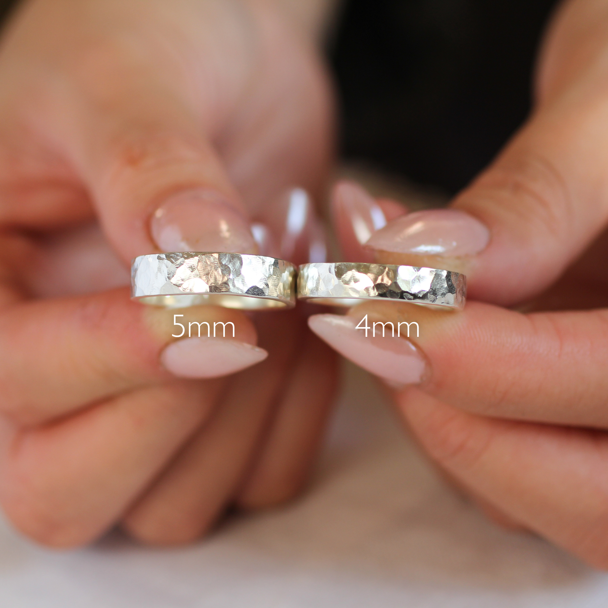 hands holding 5mm and 4mm wide hammered rings side by side to display size difference 