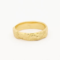 A textured gold band ring with a hammered, organic surface finish, photographed on a clean white background.