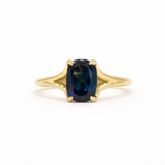 blue sapphire engagement ring with split shank on a white background