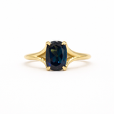 blue sapphire engagement ring with split shank on a white background