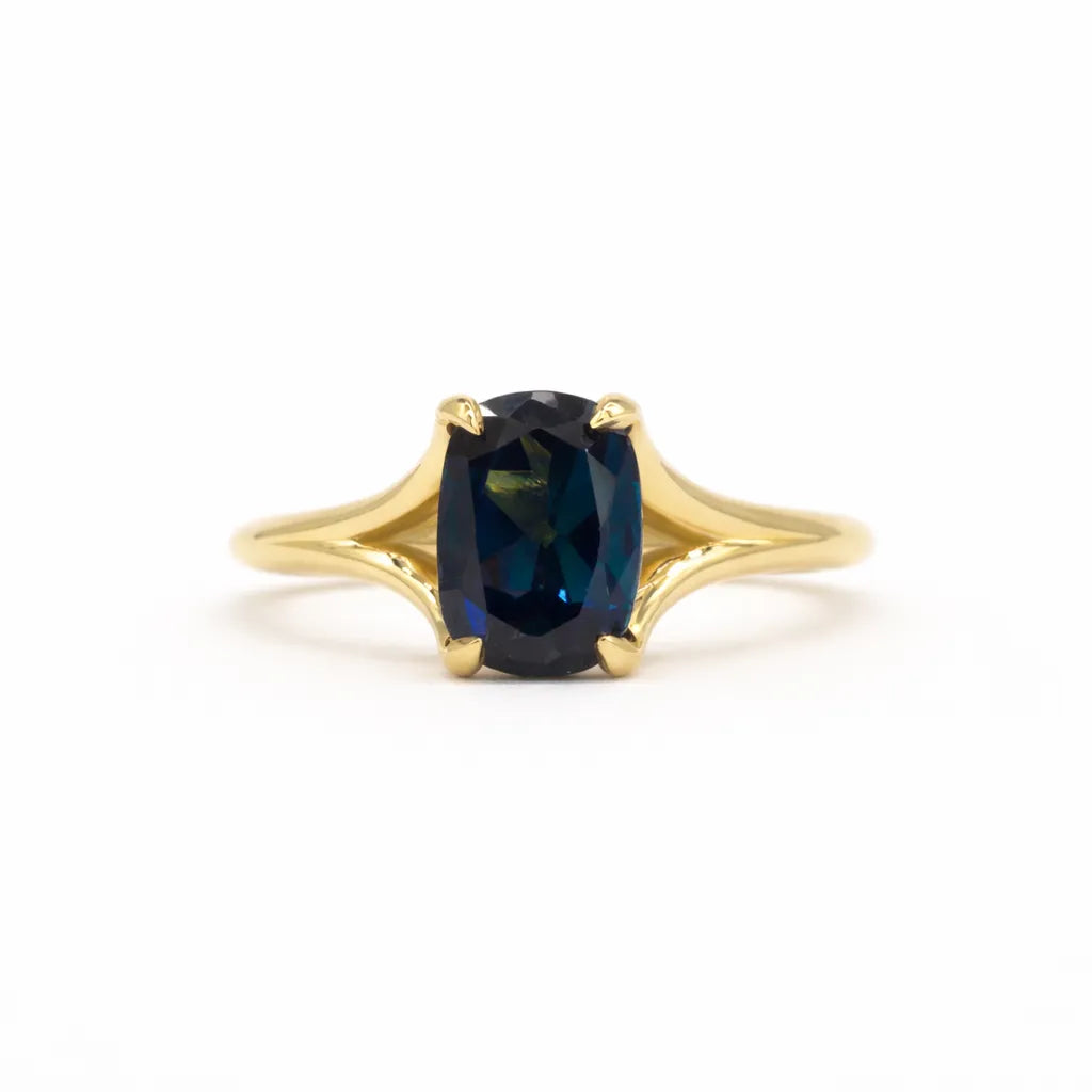 blue sapphire engagement ring with split shank on a white background