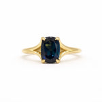 blue sapphire engagement ring with split shank on a white background