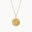 Gold necklace with a round compass pendant on a white background