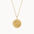 Gold necklace with a round compass pendant on a white background