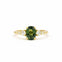 green oval sapphire engagement ring with tapered smaller diamonds on a gold band and white background