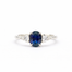 white gold engagement ring with a blue sapphire and two smaller diamonds on a white background