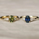 Two gold rings with gemstones on a beige fabric background