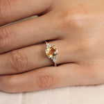 close up of hand wearing a orange sapphire engagement ring with lab grown diamonds