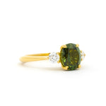 large green sapphire ring with oval stone and round diamonds on a white background