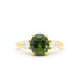 large yellow gold rounded oval green sapphire engagement ring with diamonds on a white background