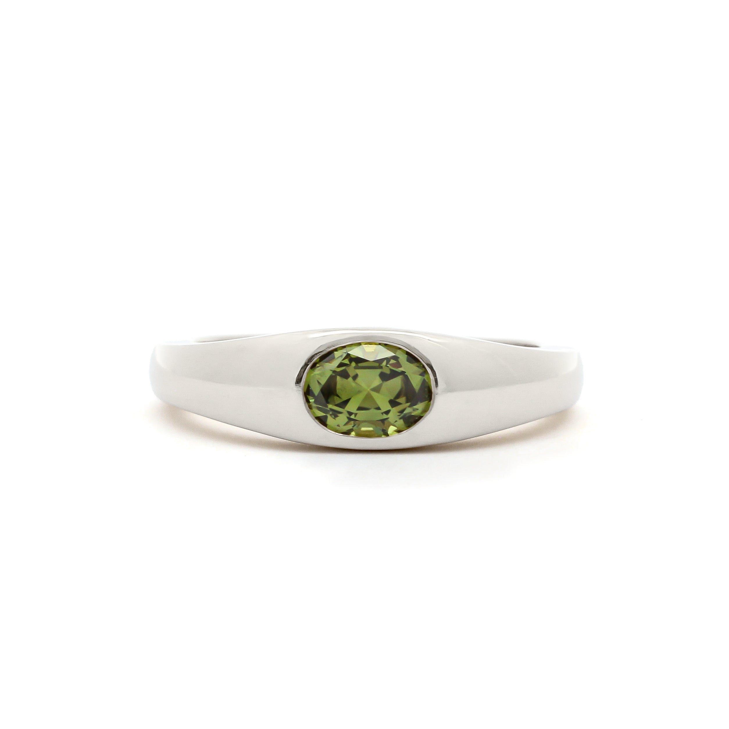 A silver-toned ring featuring a round-cut olive green gemstone in a bezel setting, presented on a clean white background.
