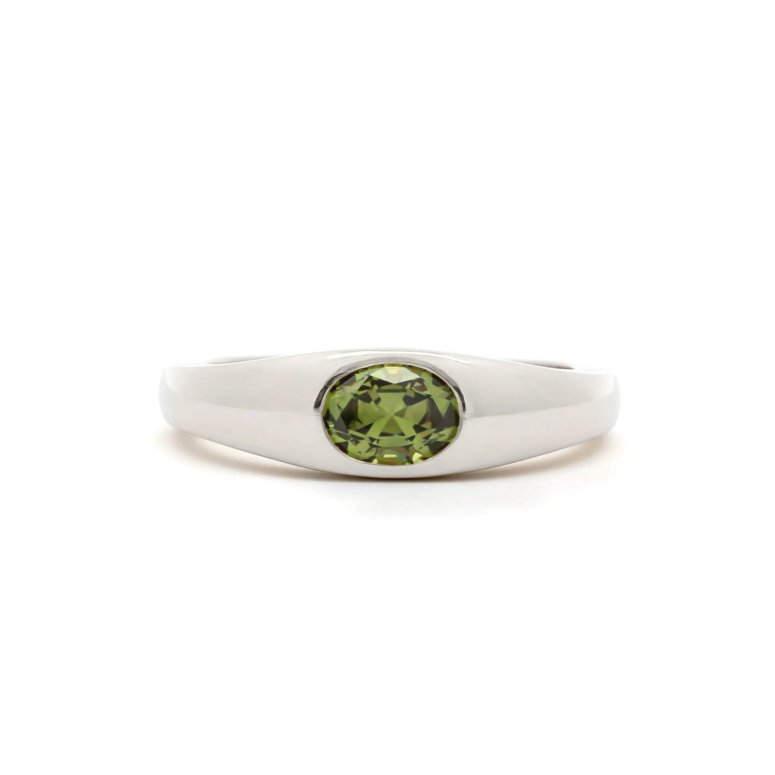A silver-toned ring featuring a round-cut olive green gemstone in a bezel setting, presented on a clean white background.
