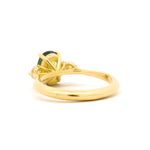 A back view of a yellow gold ring featuring a high-set green gemstone, shown against a clean white background.