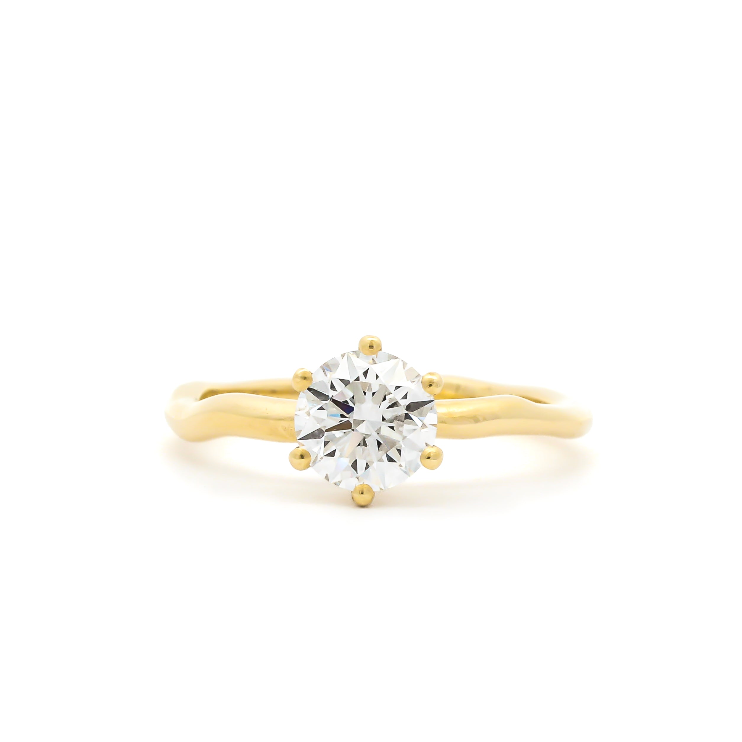 round solitaire diamond engagement ring with 6 round prongs, with wavy molten yellow gold band against a white background