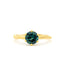 A yellow gold ring featuring a round-cut dark blue green sapphire in a 6-prong setting, shown against a plain white background.
