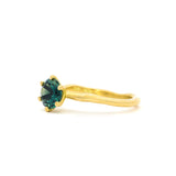 A yellow gold ring featuring a round blue green sapphire in a prong setting with an organic molten-style band, shown against a plain white background.