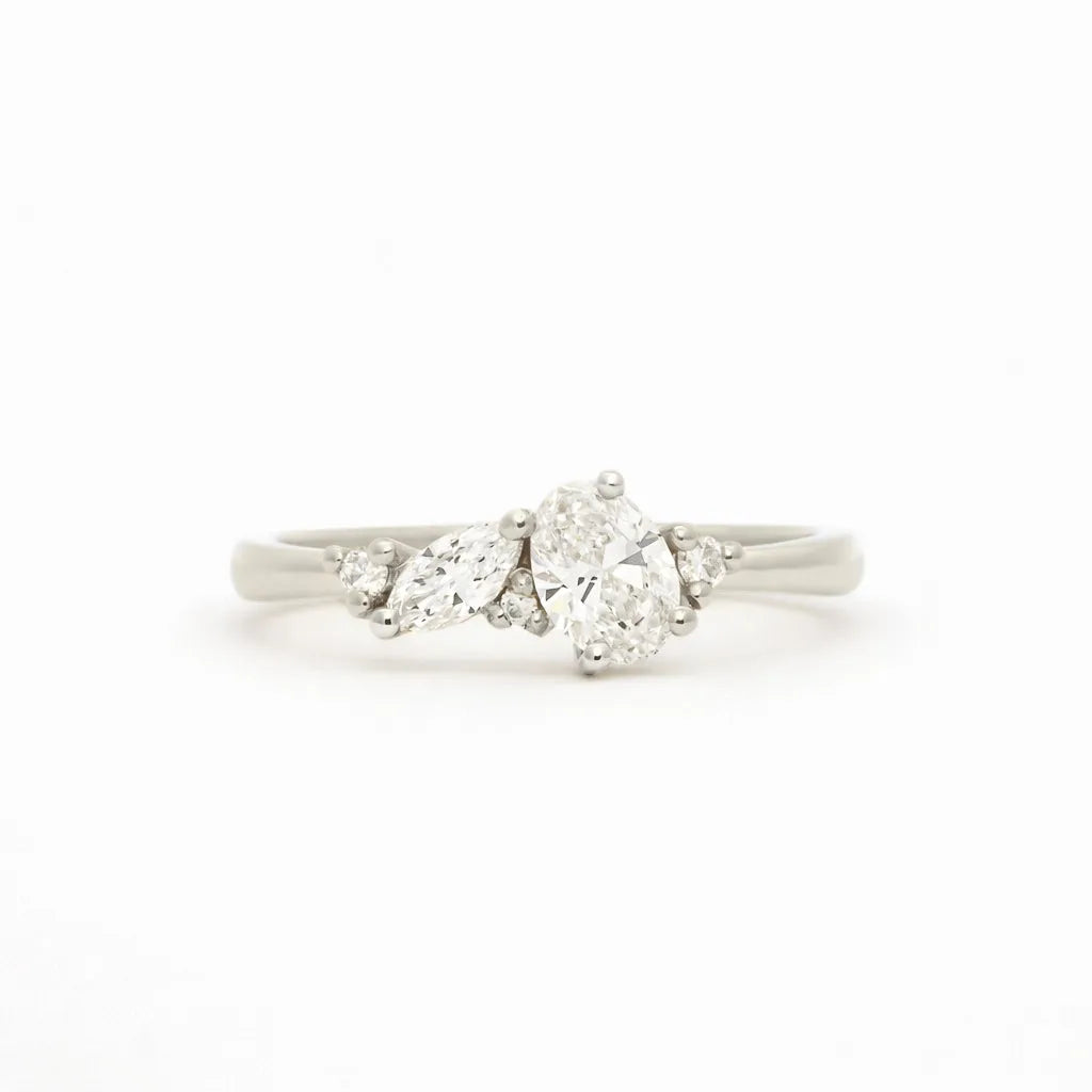 A white gold cluser diamond ring featuring a central brilliant-cut oval diamond flanked by marquise and round diamonds on a clean white background.