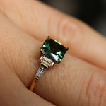 Gold ring with a green gemstone on a finger
