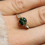 round green sapphire ring with kite diamonds close up on finger