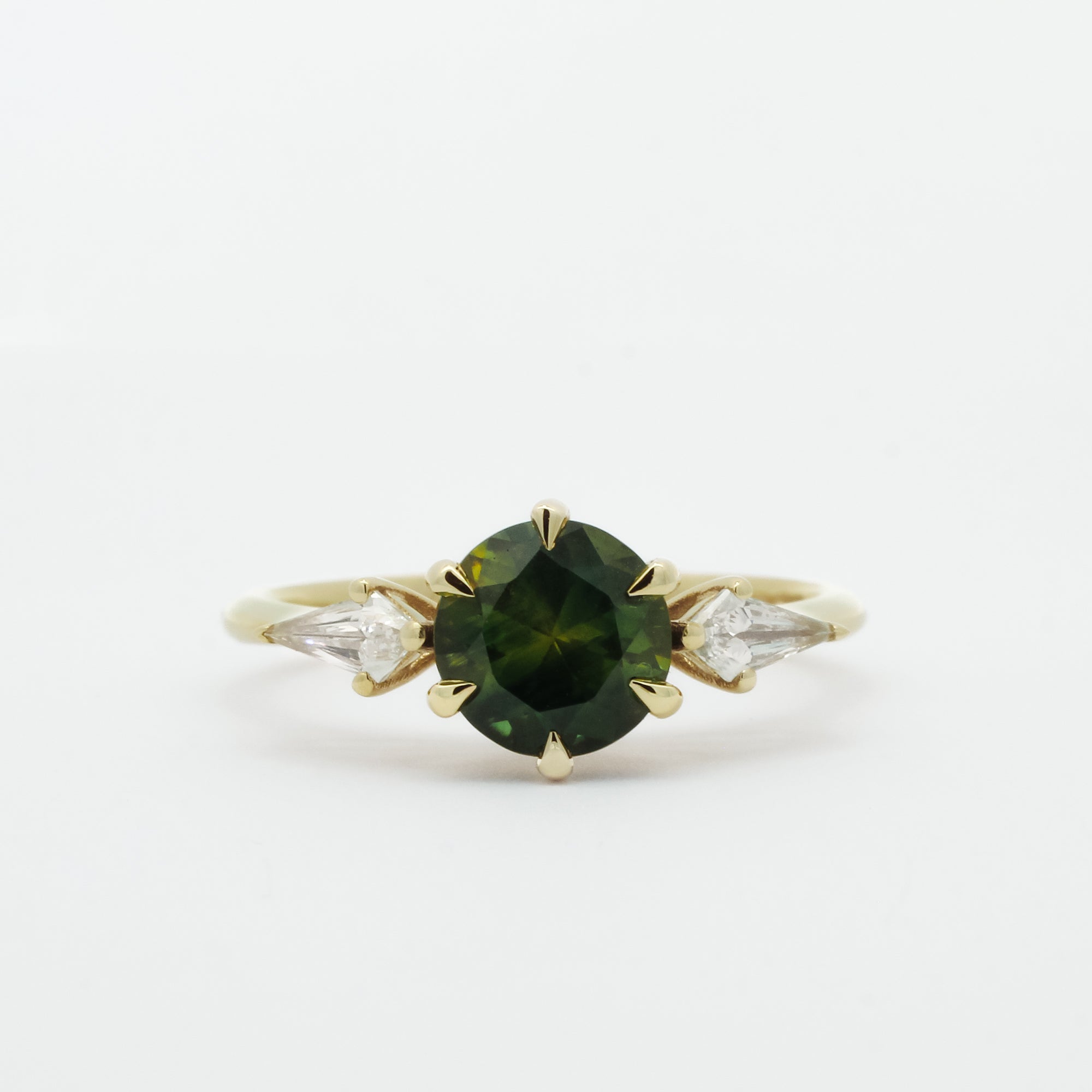 Gold ring with a dark green gemstone and two smaller kite-shaped diamonds on a white background