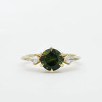 Gold ring with a dark green gemstone and two smaller kite-shaped diamonds on a white background