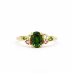 Gold ring with a green gemstone and smaller pink and green stones on a white background