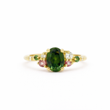 Gold ring with a green gemstone and smaller pink and green stones on a white background