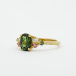side view of Gold ring with green gemstone on a white background
