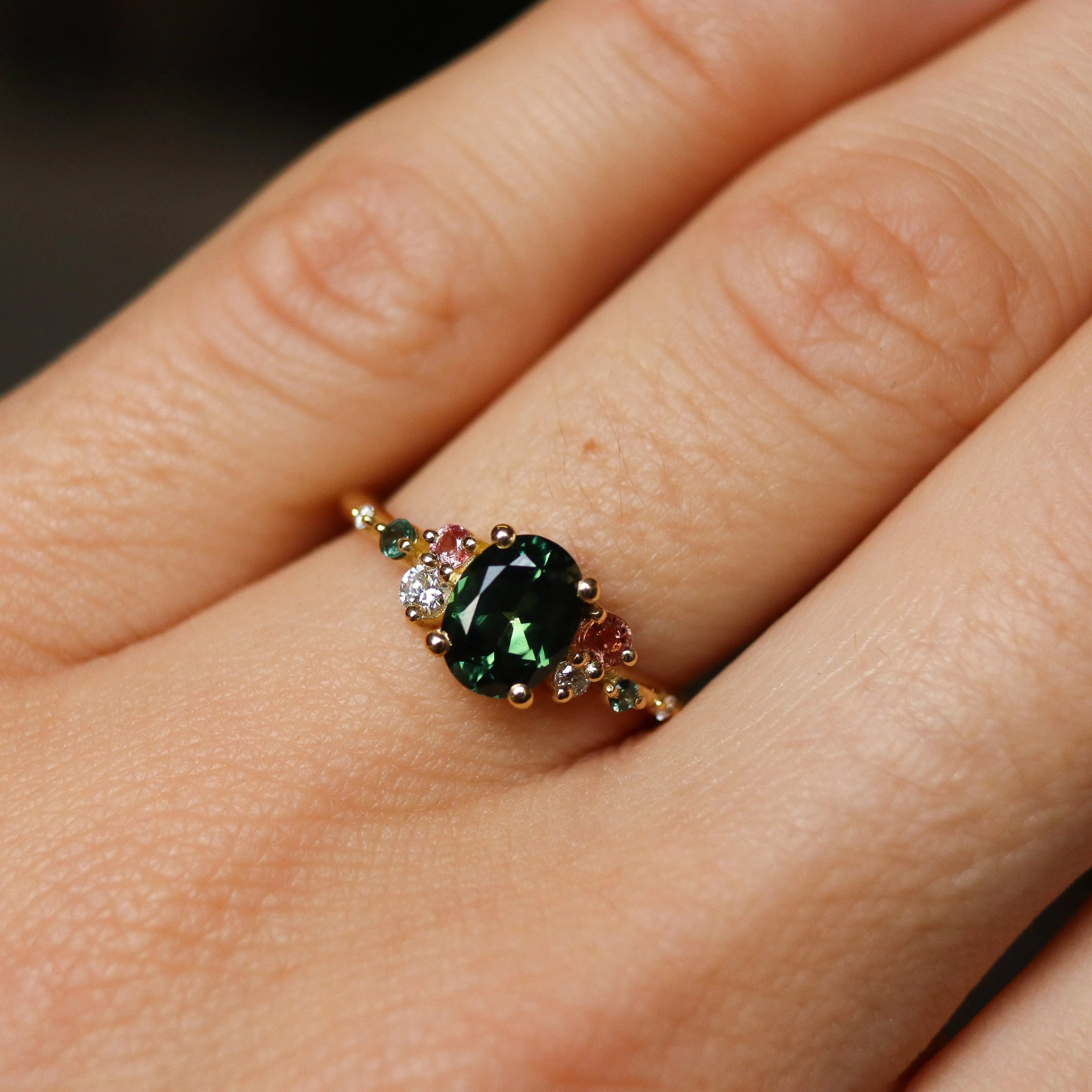green and pink engagement ring on hand