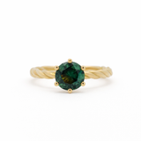 Gold engagement ring with a green round sapphire and twisted shank on a white background