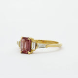 Gold ring with a peachy berry pink gemstone on a white background