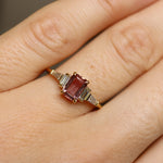 Gold ring with a red gemstone on a person's finger