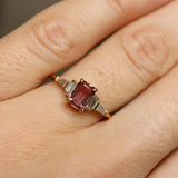 Gold ring with a red gemstone on a person's finger