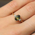 green and yellow engagement ring on finger