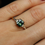 Gold ring with a green gemstone on a person's finger